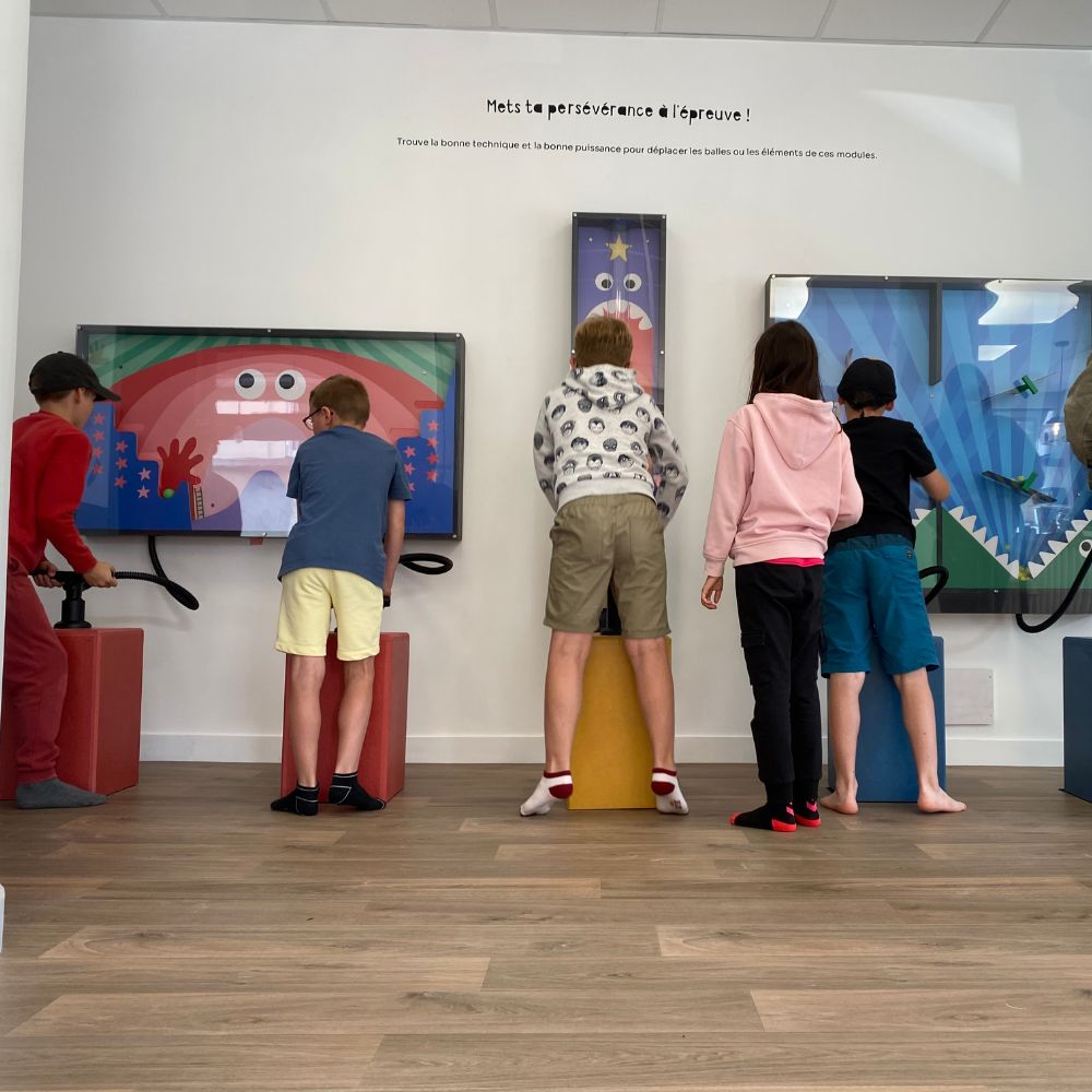 5 enfants de dos, qui jouent sur les jeux d'air de l'agence GG au musée des mômes