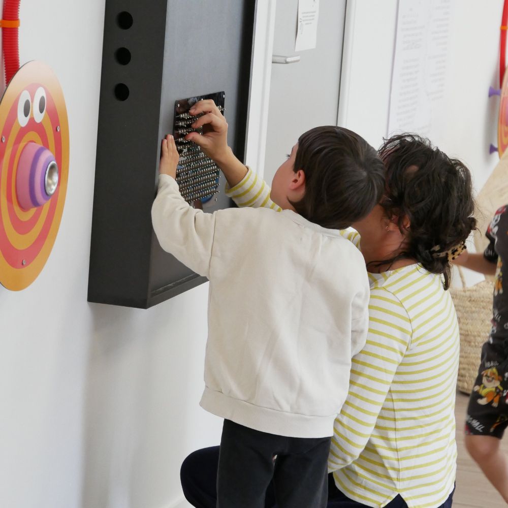 une maman et son fils à genoux en train de jouer avec le jeu de lumière de l'agence GG au musée des mômes