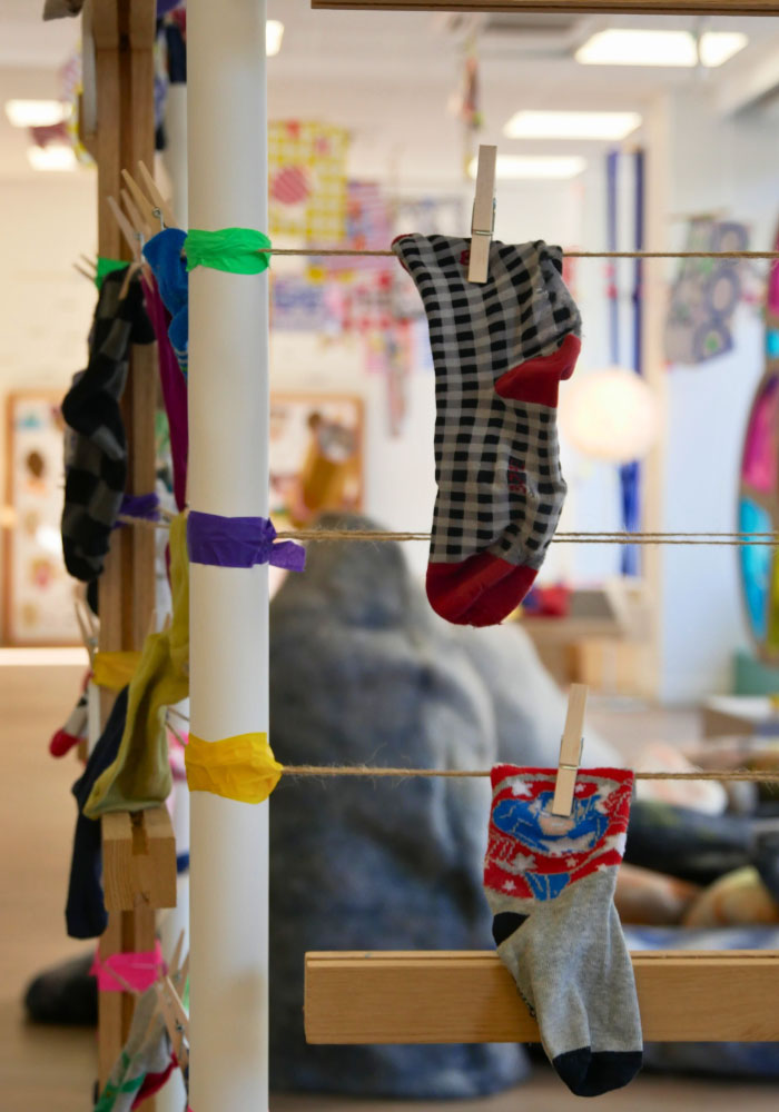 une chaussette à carreaux noir et rouge d'enfant suspendue dans la cabane à chaussettes orphelines