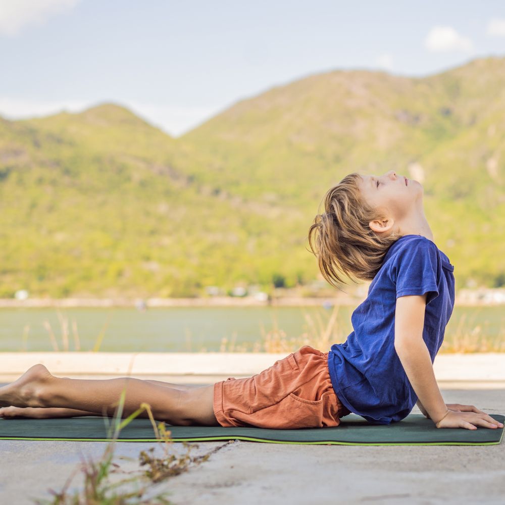 enfant en position de yoga au bord d'un lac